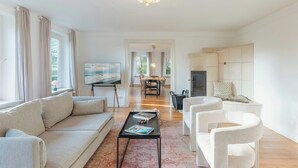 Ein geräumiges Wohnzimmer mit einer Couch, Sesseln, einem Couchtisch und einem Kamin.