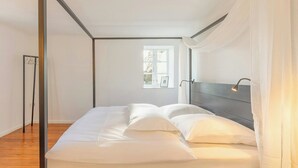 Ein Schlafzimmer mit Bett, Fenster und einer Pendelleuchte.
