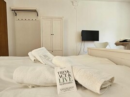 Habitación de hotel con cama, televisor, armario y toalla con un mensaje.