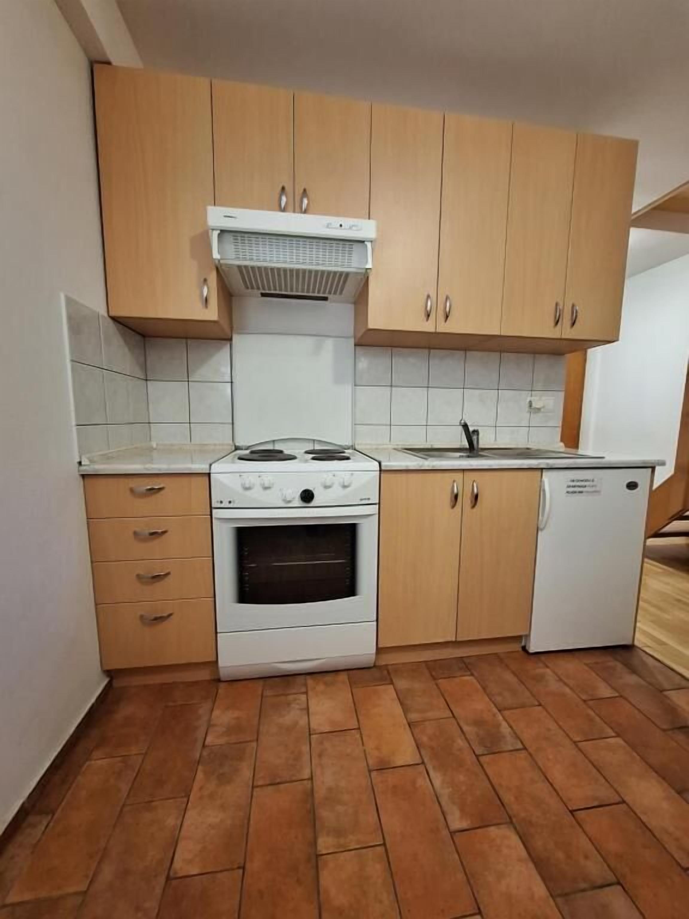 A kitchen with wooden cabinets, a stove, an oven, a sink, and a dishwasher.