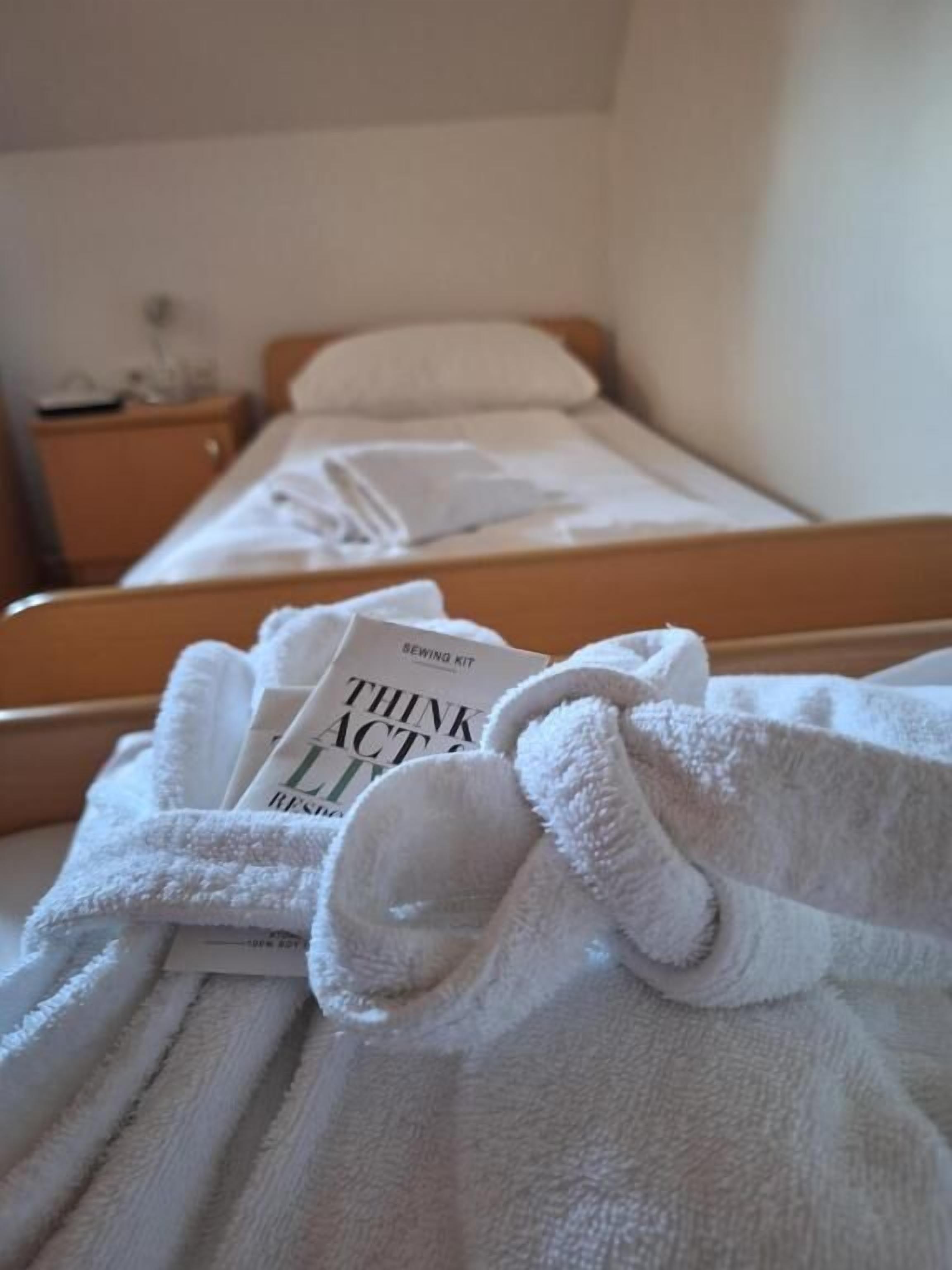 A neatly made bed with a book titled 'Think Act' beside it.