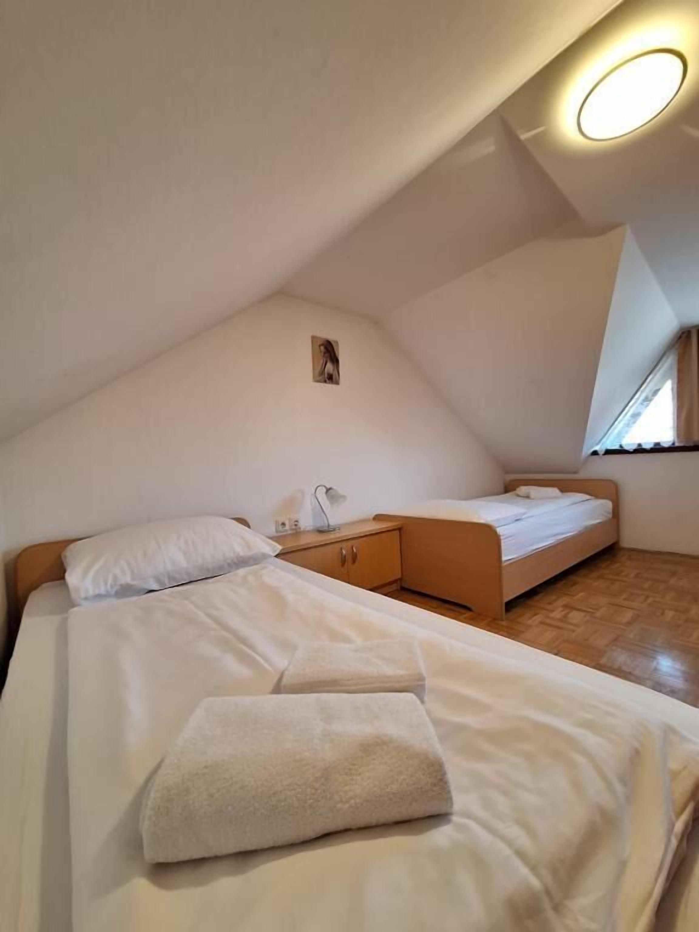 A bedroom with two beds, a bedside table, a lamp, and a small picture on the wall.