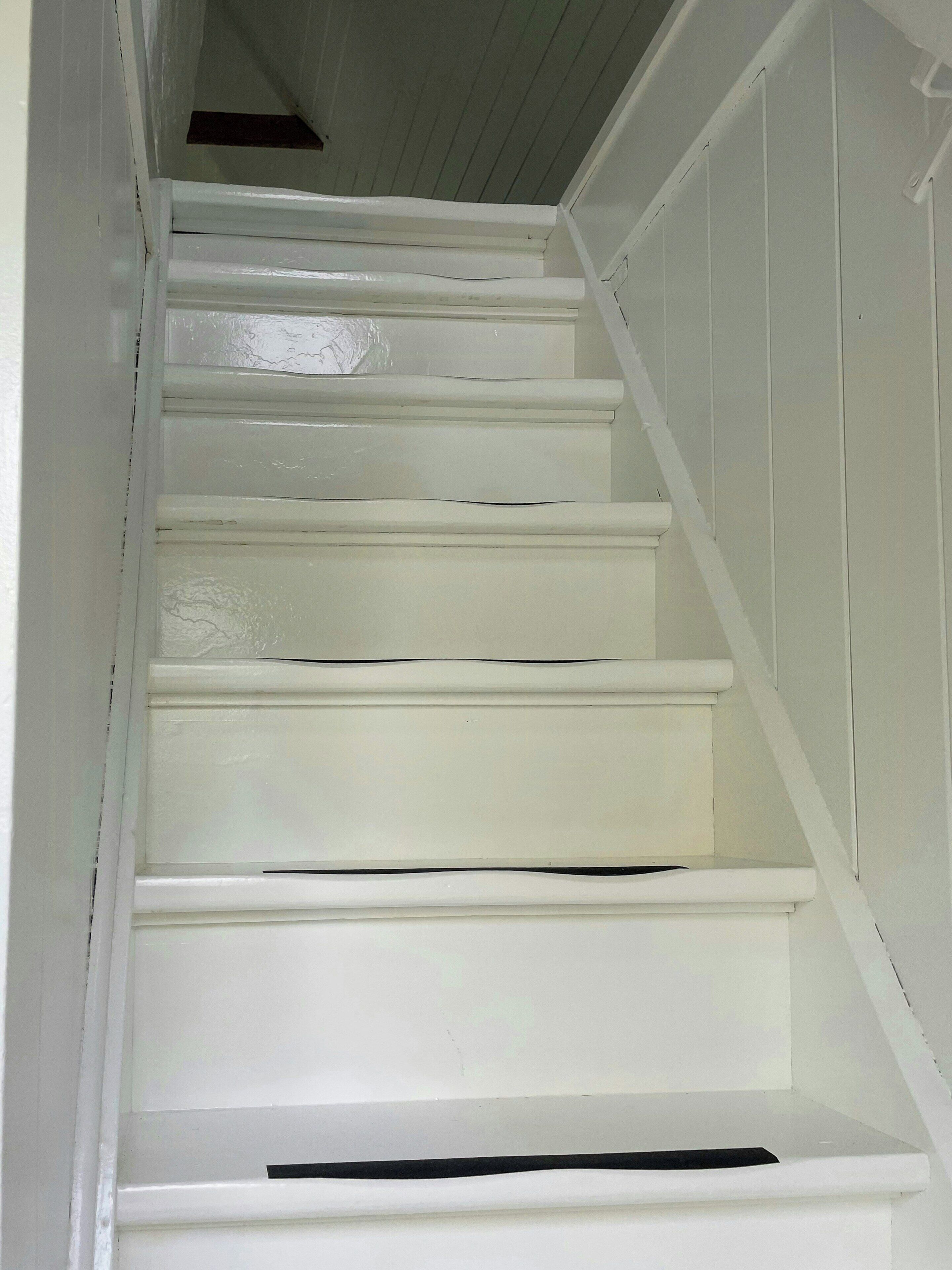 A white staircase with a handrail on the right side.