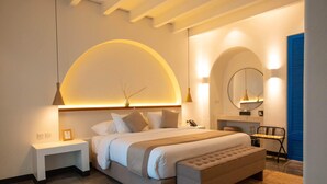 A modern bedroom with a large bed, bedside tables, a bench, and a mirror.