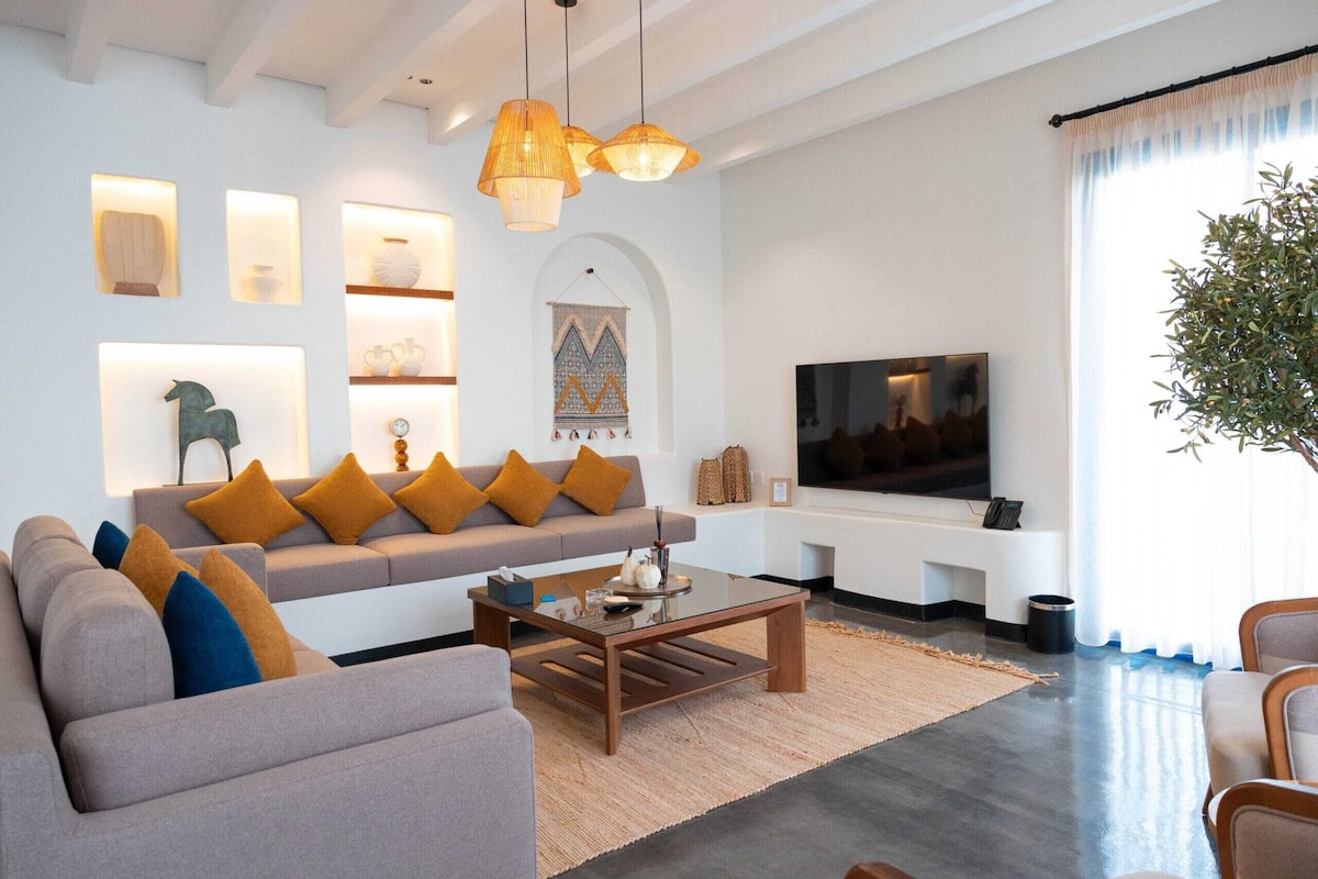 A modern living room with a sofa, coffee table, TV, and decorative wall lights.