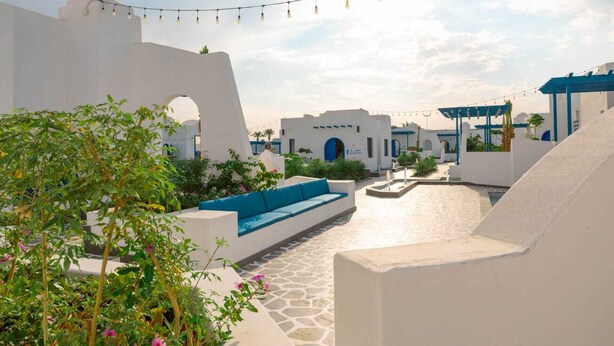 A rooftop terrace with a blue sofa, a small pool, and a pergola.