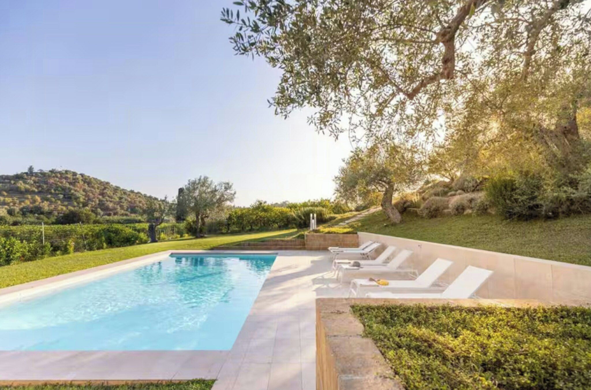 A swimming pool with lounge chairs and a view of a hilly landscape.