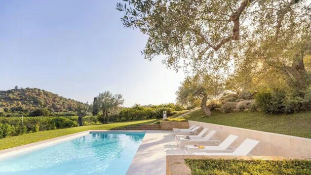 Ein Pool mit Liegestühlen und Blick auf eine hügelige Landschaft.