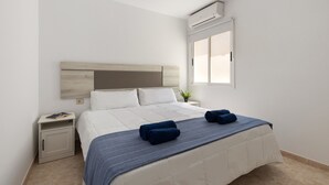 A bedroom with a bed, bedside table, nightstand, and an air conditioning unit. - Famara Cactus by Escape Home (Famara)