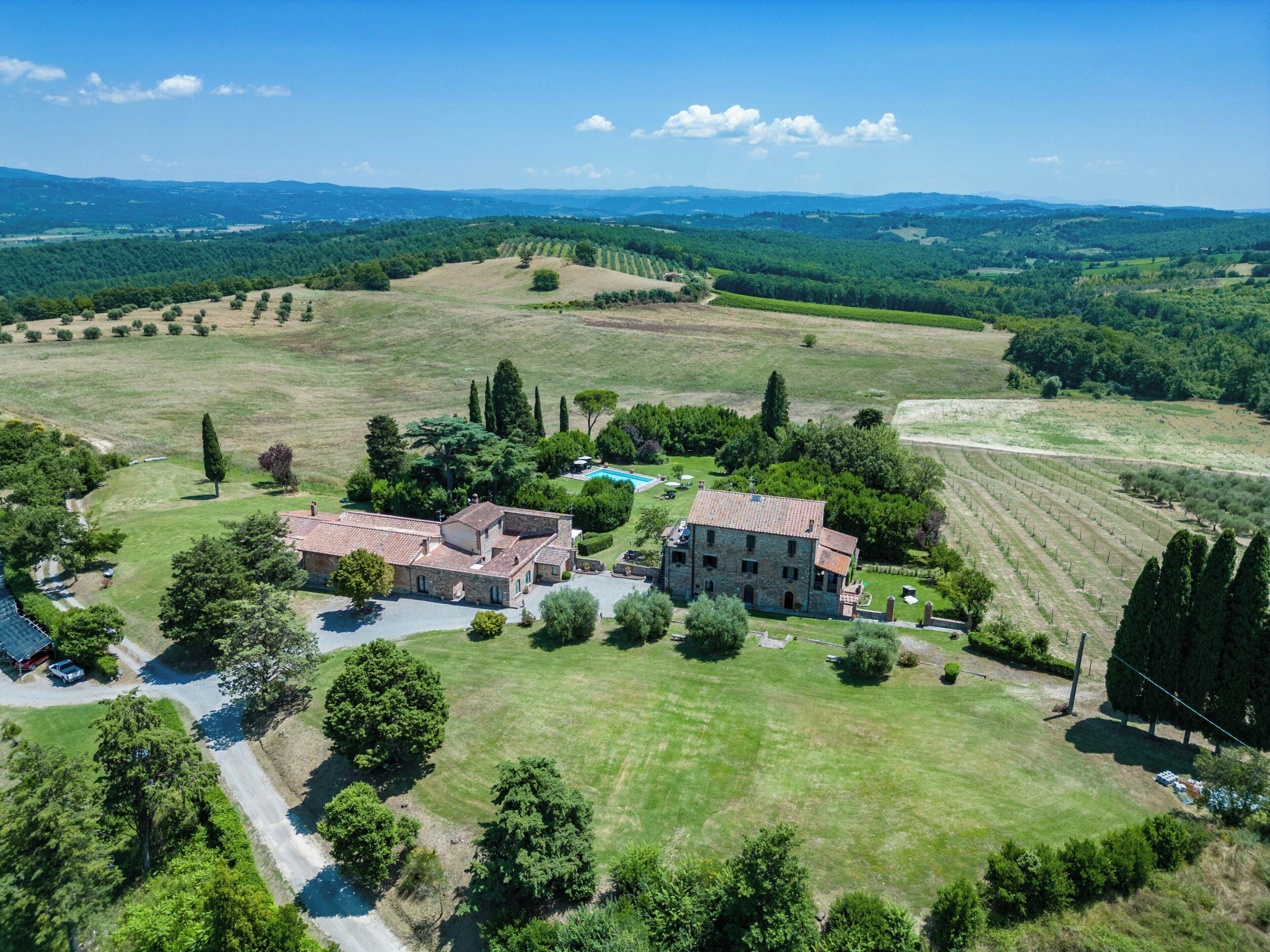 Un'ampia tenuta con diversi edifici, una piscina e vasti campi verdi.
