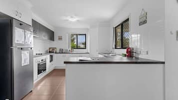 A modern kitchen with white cabinets, stainless steel appliances, and a large island.