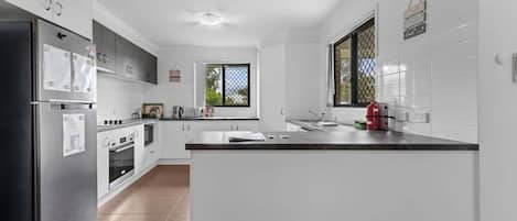 A modern kitchen with white cabinets, stainless steel appliances, and a large island.