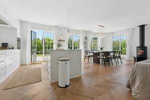 A spacious kitchen with a dining area, large windows, and a fireplace.