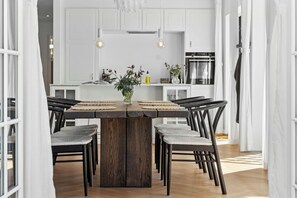 A dining area with a wooden table, chairs, and a vase of flowers.