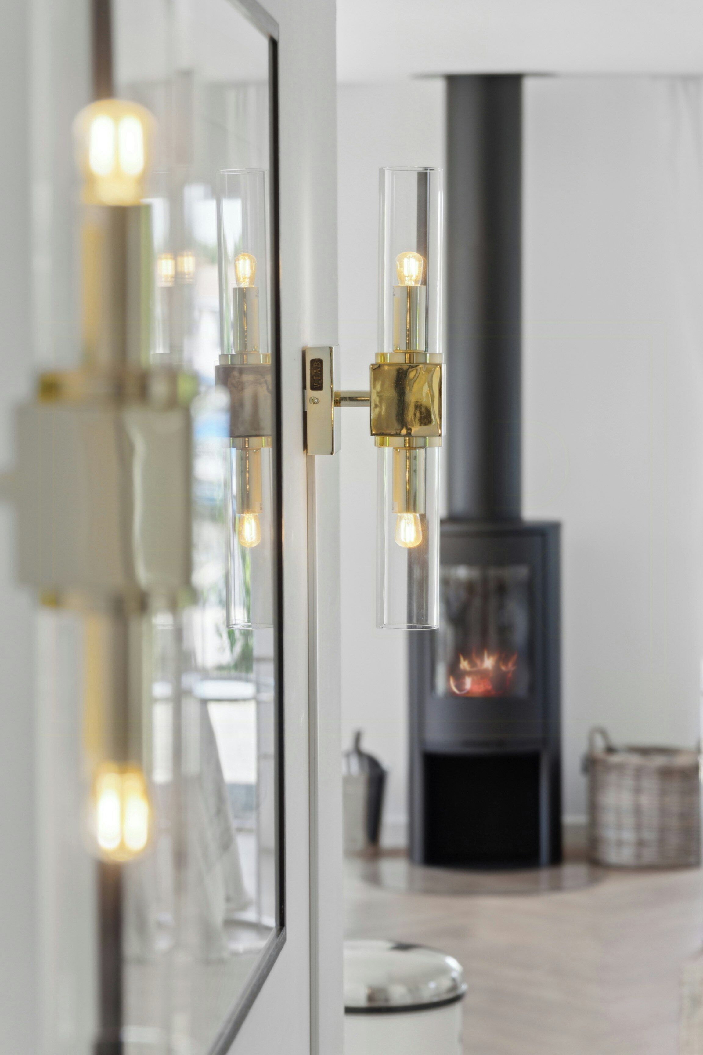 A modern interior with a glass-fronted light fixture, a fireplace, and a reflective surface.