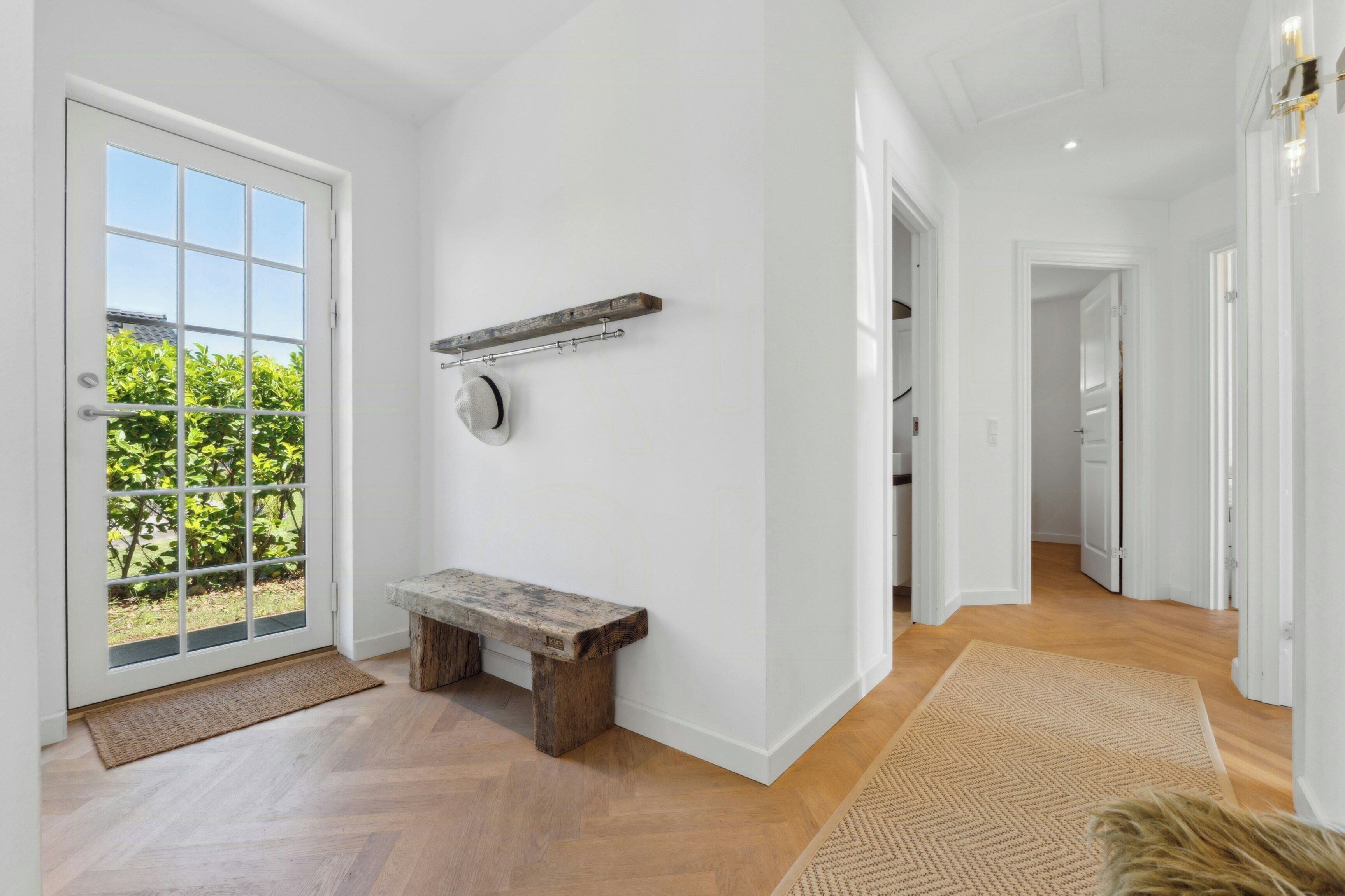 A spacious hallway with a bench, a coat rack, and a door leading to a balcony.