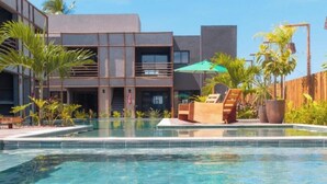 A modern hotel with a swimming pool, outdoor seating, and tropical plants. - Gamboa Oasis Patacho 180m from the beach on the Ecological Route of Miracles (Porto de Pedras)
