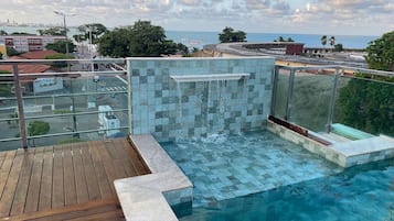 Una piscina sul tetto con vista chiara sullo skyline cittadino e sul mare.