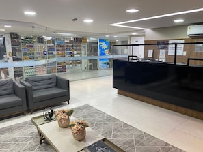 Ein Empfangsbereich mit einem schwarzen Empfangstresen, grauen Sofas und einer Glasvitrine mit Produkten.