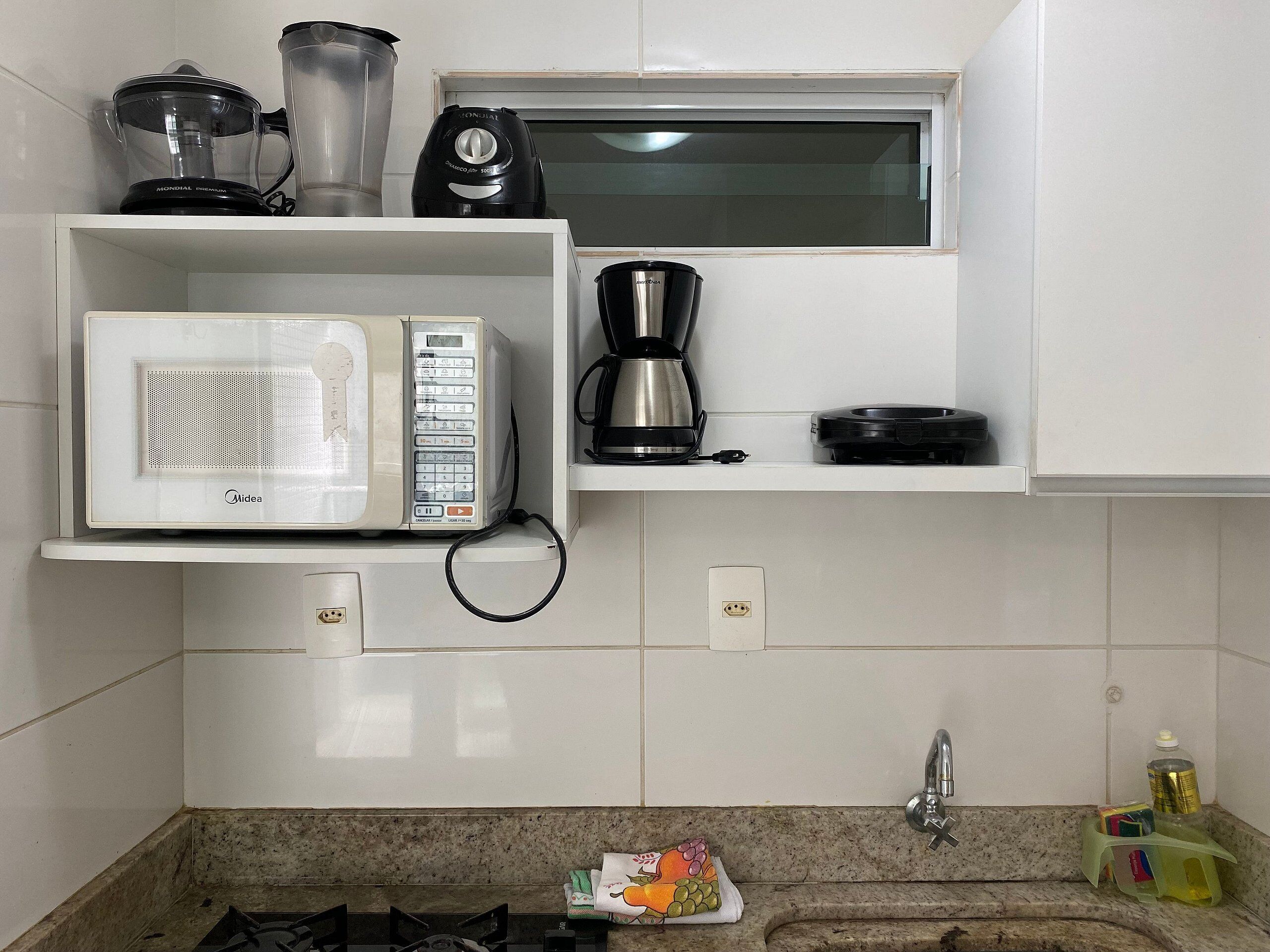 Una cocina con microondas, cafetera y licuadora en la encimera.