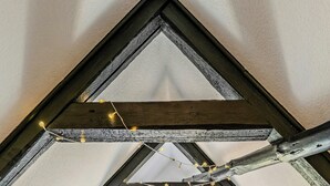 Ein Schlafzimmer im Loft-Stil mit schrägem Dach, einem Bett mit Kopfteil und Blick durch eine Tür auf einen Außenbereich.
