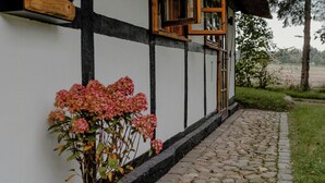 Ein traditionelles Gebäude mit einem Reetdach, einem Steinweg und einem Blumentopf mit rosa Blüten.