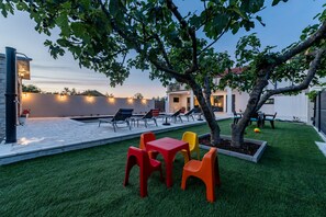 A patio with a pool, outdoor seating, and a tree. - Villa Flora Zadar Villas (Benkovac)