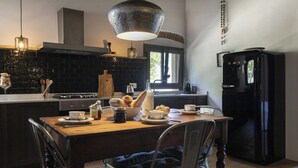 Une cuisine équipée d’une table à manger, de chaises, d’un réfrigérateur et d’un luminaire suspendu.