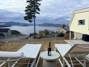 A view of a lake with a mountain in the background, a tall tree, and a building with a white exterior. - Modern cabin with panoramic views near Kragerø (Stabbestad)