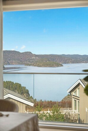 A view of a lake with forested hills in the background, a house with a balcony, and a clear sky. - Modern cabin with panoramic views near Kragerø (Stabbestad)