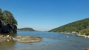 Ein klarer Blick auf einen stillen See mit felsigen Ufern und weit entfernten Hügeln.
