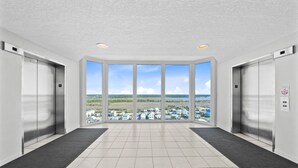 A modern elevator area with large windows, a tiled floor, and two elevators. - Stunning Gulf Front Views | Beach Access | Indoor & Outdoor Pools (Gulf Shores)