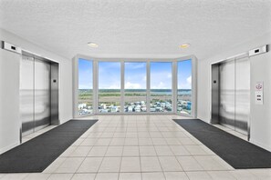 A modern elevator area with large windows, a tiled floor, and two elevators. - Stunning Gulf Front Views | Beach Access | Indoor & Outdoor Pools (Gulf Shores)