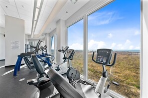 Ein Fitnessraum mit Cardiogeräten und großen Fenstern mit Blick ins Freie.