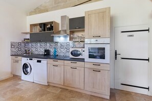 Cozinha moderna com máquina de lavar, micro-ondas, forno e armários de madeira.