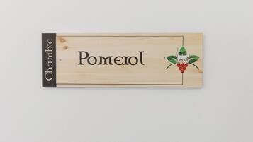 Une enseigne en bois portant le nom « Pomerol » et un logo représentant un chat et des raisins.