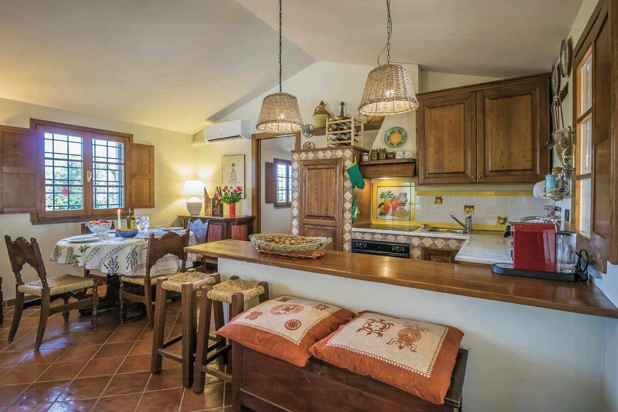 A kitchen with wooden cabinets, a dining table with chairs, and a bar area with stools.