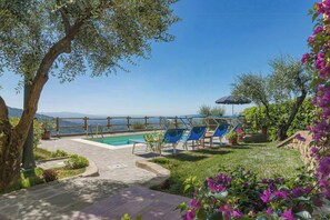Un'area piscina con lettini, un solarium in legno e vista mare.