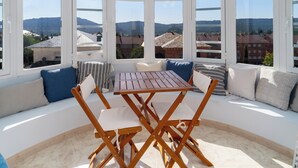 A sunlit room with a view of mountains, a wooden table, and cushioned seating.
