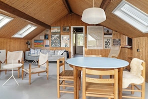 A loft-style room with a high ceiling, wooden walls, a round table, and several chairs. - Slow living by the water on Sejerø (Sejerø)