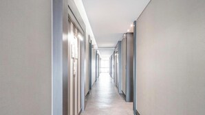 Un pasillo largo y estrecho con puertas a ambos lados, que conduce a habitaciones individuales.