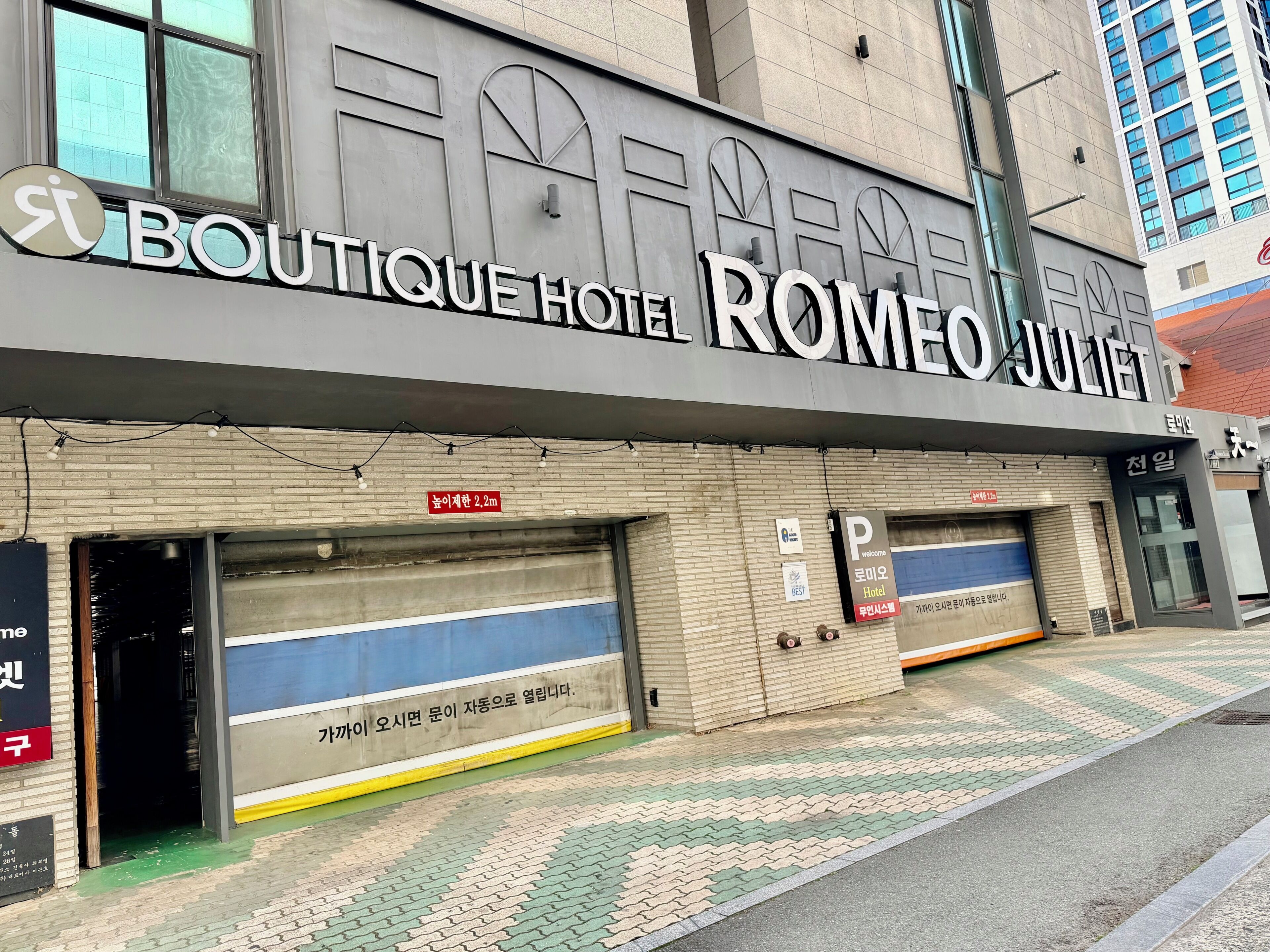 A hotel facade with 'BOUTIQUE HOTEL ROMEO JULIET' signage, a parking sign, and a fire hydrant.