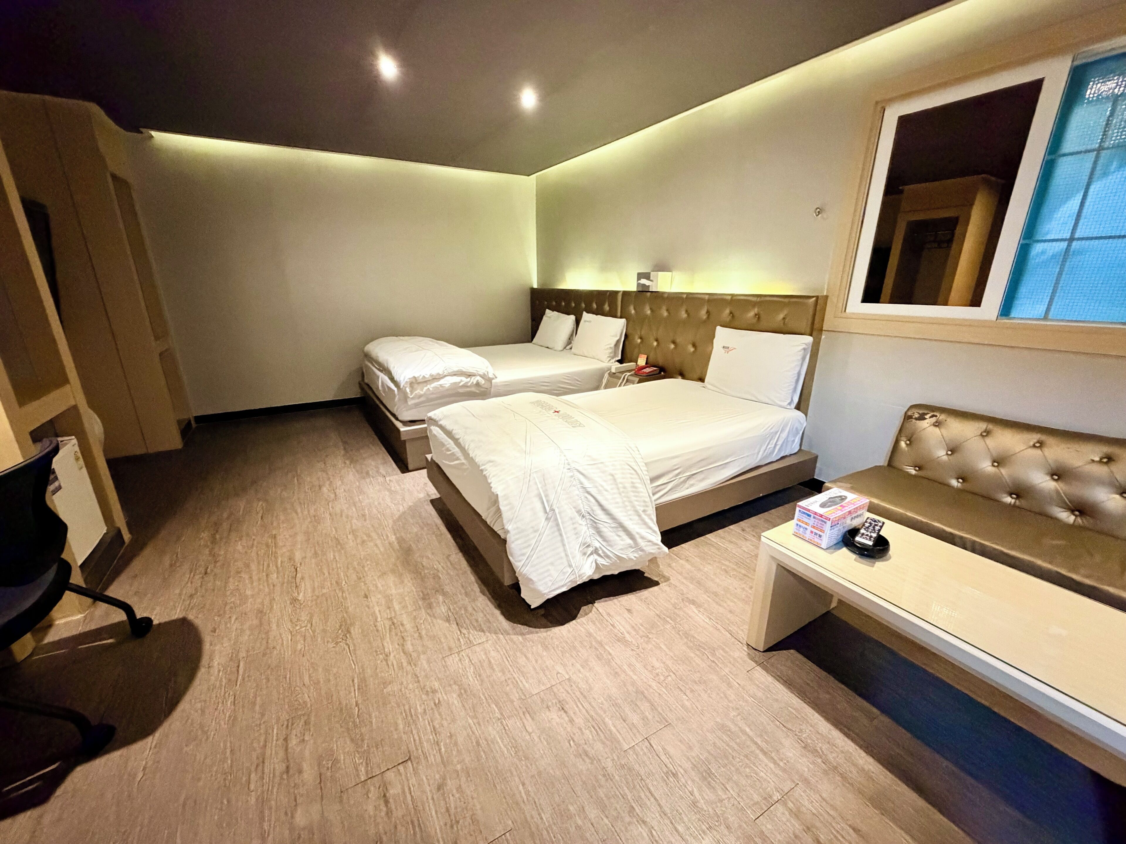 A hotel room with two beds, a sofa, a desk, and a mirror.