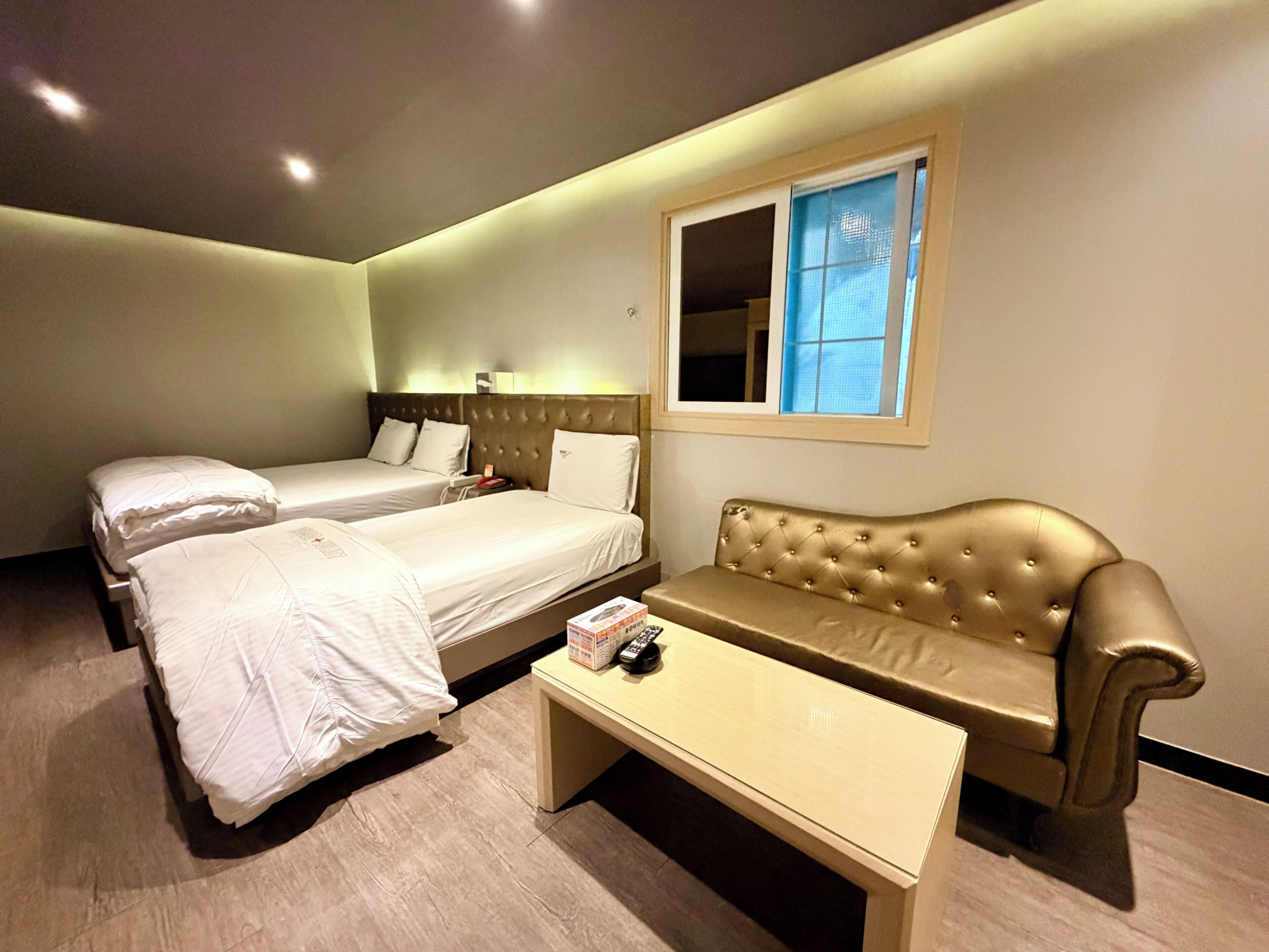 Ein Hotelzimmer mit zwei Betten, einer Couch, einem kleinen Tisch und einem Fenster.