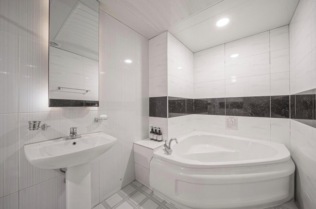 Un baño moderno con un lavamanos blanco, una bañera y un espejo.