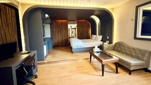 Una habitación de hotel con cama, sofá, escritorio y televisor.
