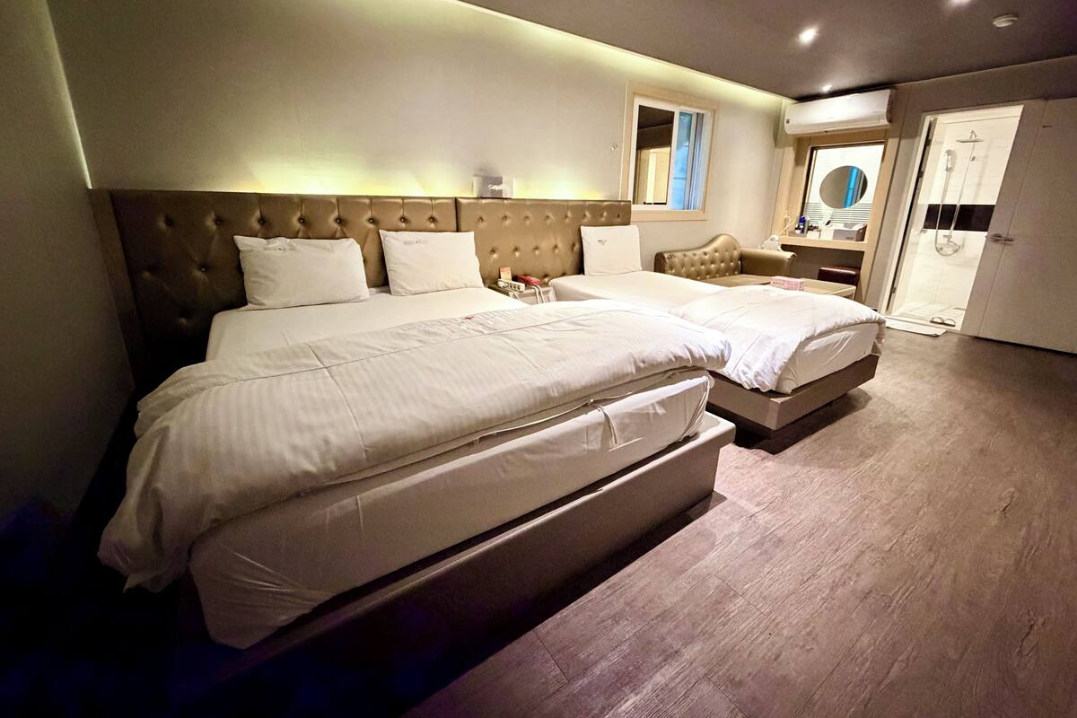 A hotel room with a large bed, a bedside table, a mirror, and a wardrobe.