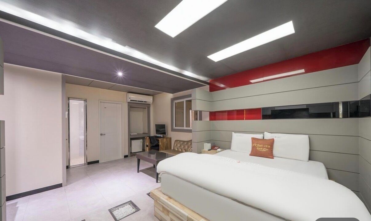 Une chambre d’hôtel moderne équipée d’un lit, d’une table de chevet et d’un petit bureau.