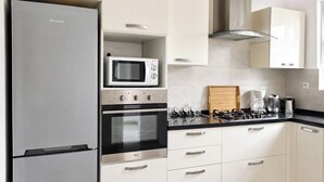 Uma cozinha moderna com geladeira Brandt, micro-ondas, forno e fogão a gás.