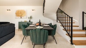 A dining area with a dark table, green chairs, and a staircase with black railings. - Villa Flora Zadar Villas (Benkovac)